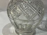 un vase en verre posé sur une table à côté d'un bougeoir en verre