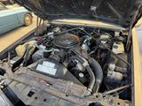a car engine with its hood open and a car in the background