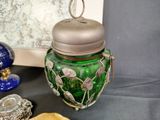 a green glass jar with a silver lid on a table