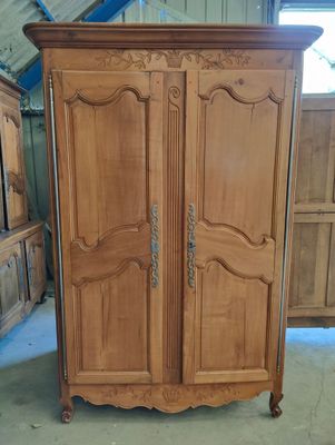 a wooden armoire in a room with many wooden cabinets