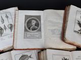 many old books with birds on them sitting on a table