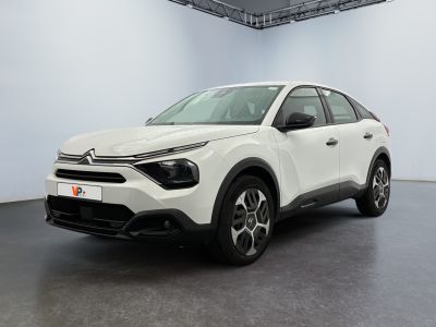 Une voiture blanche est garée dans une pièce blanche au sol noir.