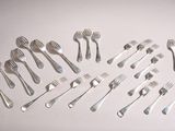 de nombreuses fourchettes et cuillères disposées sur une surface blanche
