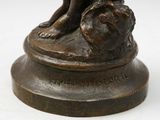 bronze statue of a dog sitting on a rock with a ball in its mouth