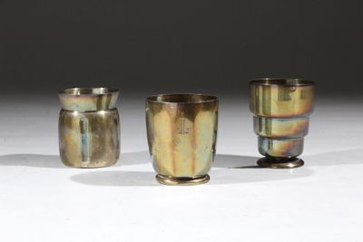 trois vases en argent posés sur une surface blanche
