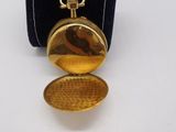 an image of a gold pocket watch sitting on top of a black case