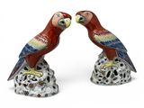 pair of red and green parrots sitting on top of a tree stump