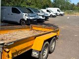a yellow flatbed truck with a flat bed in a parking lot