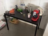 une table noire sur laquelle est posée une cafetière rouge