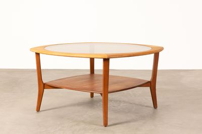 une table basse ronde avec un plateau en verre posée sur un sol en béton