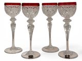four wine glasses with red rims are lined up on top of each other