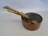 five metal spoons in a metal bowl on a white surface