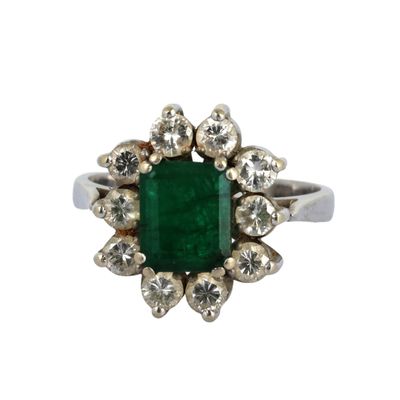 une image d'une bague avec une pierre verte entourée de diamants blancs