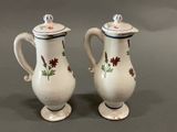 two white vases with flowers on them on a table