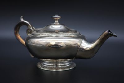 a silver tea pot on a black table