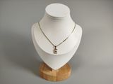 collier posé sur un mannequin posé sur un socle en bois, devant un fond blanc