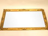 une image d'un miroir encadré d'or sur un mur blanc