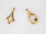 two gold pendants with a black diamond and a red stone