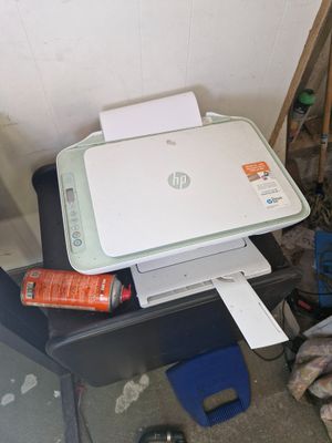 a printer sitting on top of a desk next to a pile of clutter