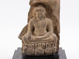 une statue en pierre représentant un Bouddha assis sur un socle noir