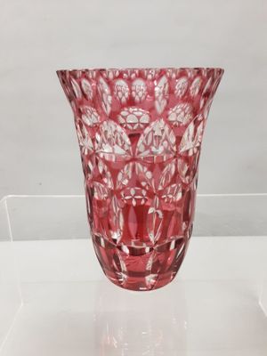 a red glass vase sitting on a clear shelf