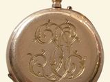 a gold pocket watch with a monogram on it