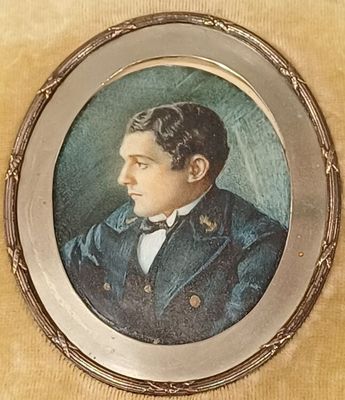 portrait d'un homme en costume et nœud papillon, dans un cadre argenté