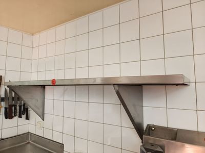 une cuisine équipée d'un évier et d'une étagère en métal