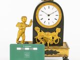 a small statue of a boy holding a credit card next to a clock