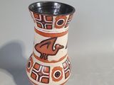 a small vase with a bird on it on a table