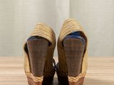 pair of women ' s espadrills on a wooden table with a curtain in the background