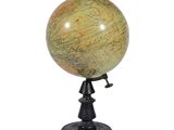 un gros plan d'un petit globe terrestre posé sur un socle, sur fond blanc