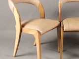 two wooden chairs with leather upholstered seats against a gray background