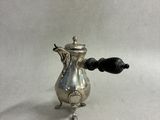 an antique silver coffee pot with a black handle on a white background