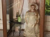 une poupée dans une vitrine posée sur une table