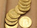 un tas de pièces d'or posées sur une table, à côté d'un penny