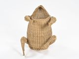 a basket with a frog on it sitting on a white surface