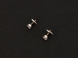 a pair of diamond stud earrings on a black surface