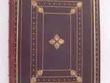 un livre marron aux bords dorés sur une couverture blanche