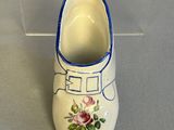 a white shoe with blue trim and flowers painted on it