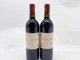 deux bouteilles de vin rouge posées l'une à côté de l'autre sur une surface blanche