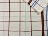un gros plan sur une chemise blanche à carreaux marron et bleus