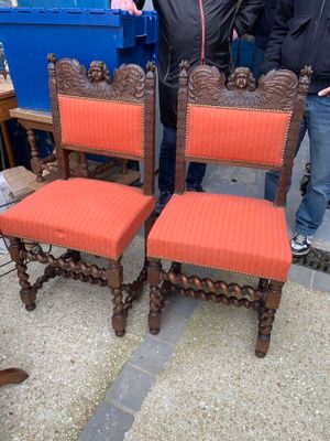 two men standing next to each other near a set of chairs