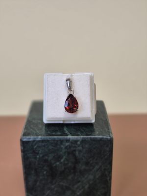 un gros plan d'une bague sertie d'une pierre rouge, posée sur un bloc de marbre