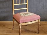 une chaise avec un coussin rose, placée devant un mur gris