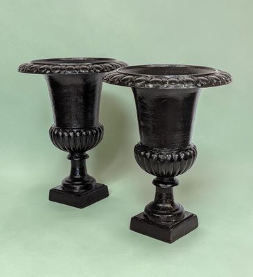 two black vases sitting next to each other on a table