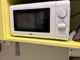 a microwave that is on a yellow shelf above a sink