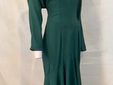 green dress on a mannequin base with a white shirt underneath it