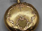 an image of a gold pocket watch with a chain on a gray surface