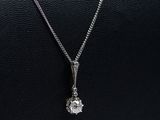 un collier en or blanc orné d'un pendentif en diamant, monté sur un cordon en cuir noir